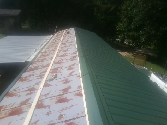 Old rusted panels beside newly installed green metal roofing — Wind Damage Roof Repair by Roofing Brothers in Winter Garden