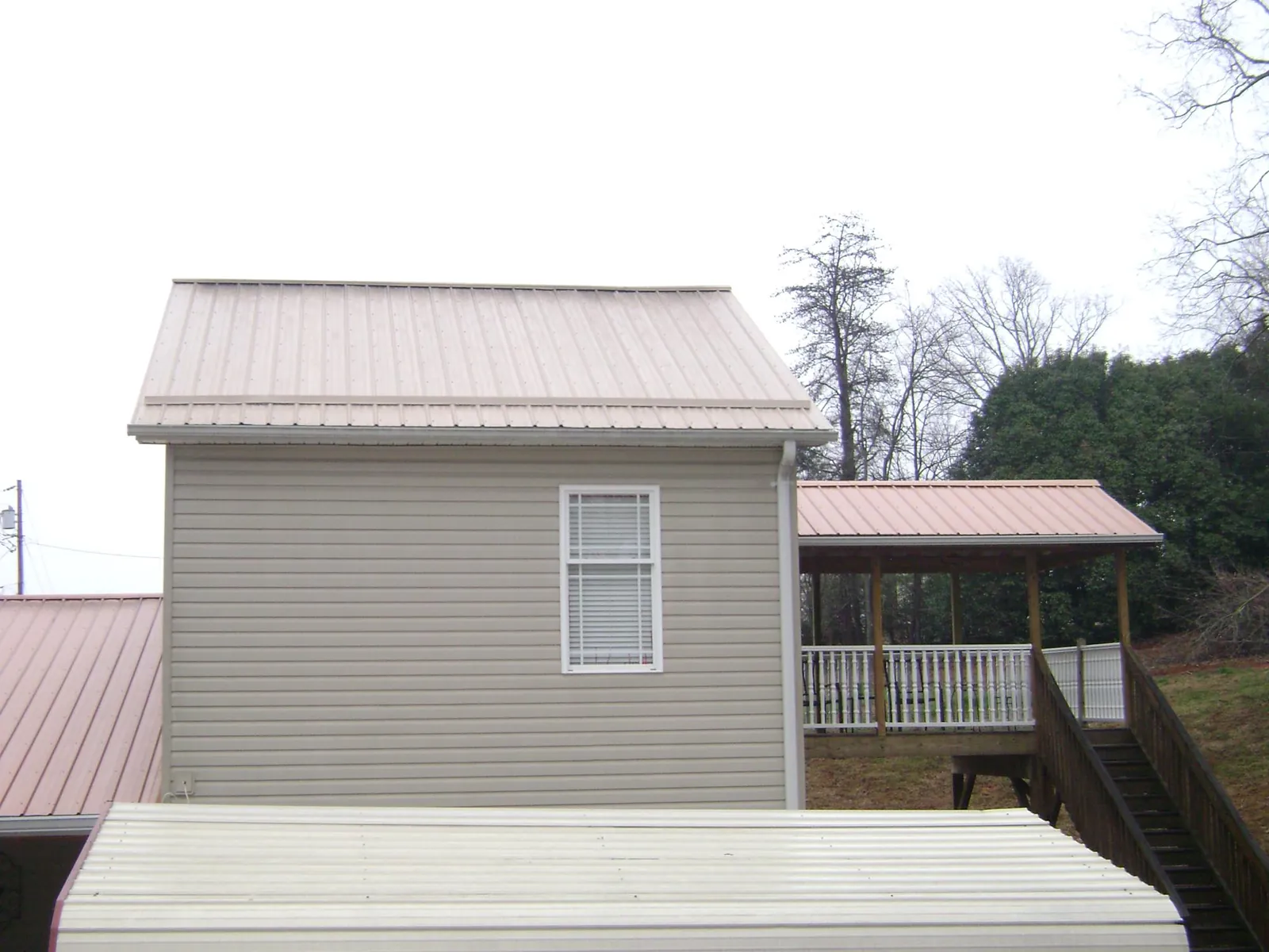 Tan metal roofs on a two story addition and attached porch, from a Roof Replacement job in Winter Garden